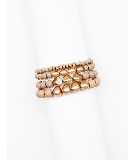A stack of three beaded stretch bracelets in a warm metallic rose gold tone, displayed on a white cylindrical mannequin arm against a white background.