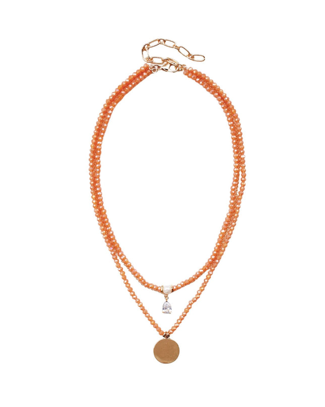 A double-strand beaded necklace in a warm peach-orange color with a small silver-toned charm and a round gold-toned disc pendant, displayed on a clean white background.