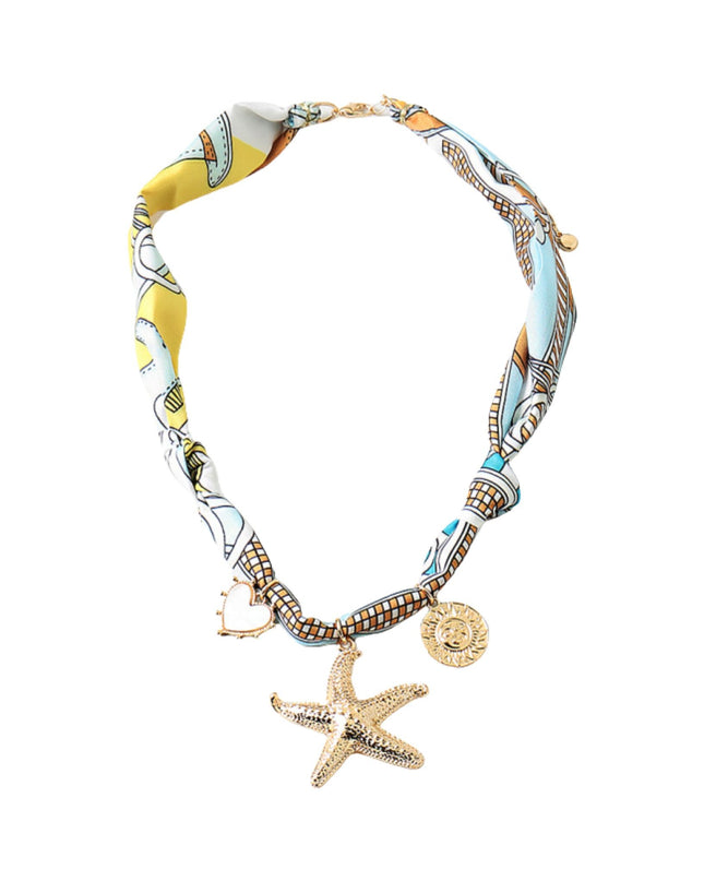 A fashion statement necklace featuring a twisted silk scarf with a yellow, blue, and white pattern, embellished with a gold starfish charm and a small gold medallion, set against a plain white background.