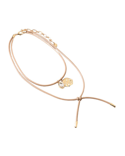 A delicate double-strand rope necklace in a warm beige or blush tone with gold-toned hardware, a small round gold charm, and a clear faceted crystal accent, displayed on a solid white background.