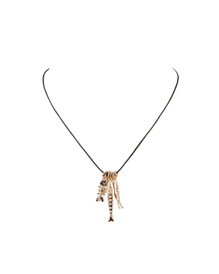 A gold-toned pendant necklace featuring a central skull-like charm with hanging bone or feather details, suspended on a thin black cord against a plain white background.