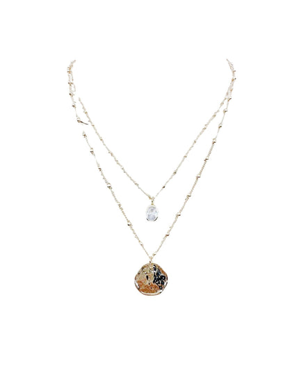 A double-strand necklace featuring a delicate gold chain with tiny beads and a larger chain with a textured, organic-shaped brown pendant, displayed on a solid white background.