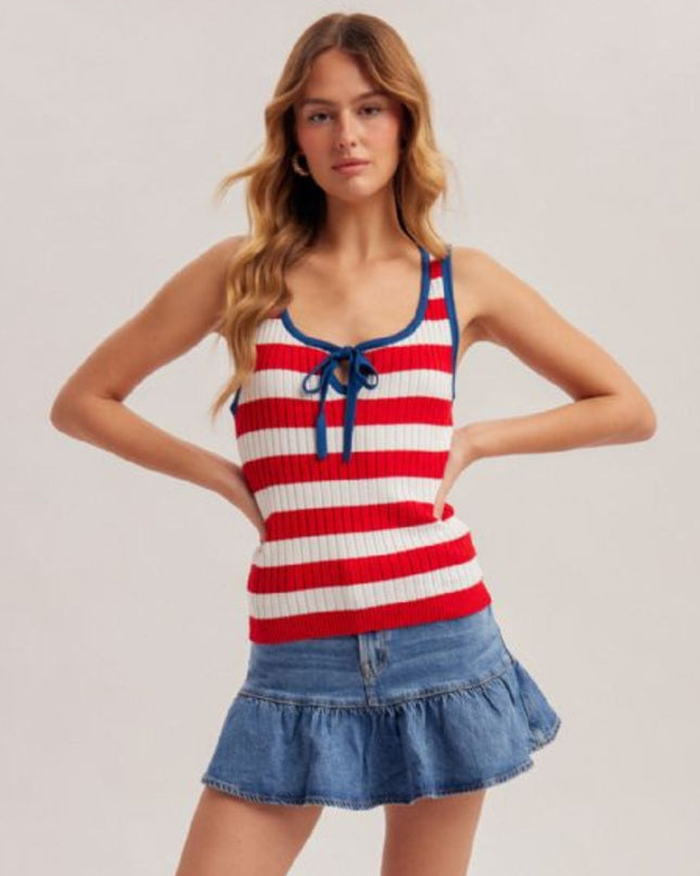 Woman wearing a red and white striped tank top with blue accents and a denim skirt on a light gray background