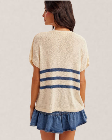 Woman wearing a beige top with blue stripes and denim skirt on a plain background