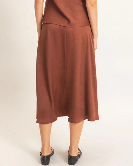 A woman wearing a rust-brown midi skirt with a matching top, shown from the back against a plain light background.
