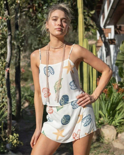 Woman wearing a white dress with colorful sea-themed patterns in a garden setting