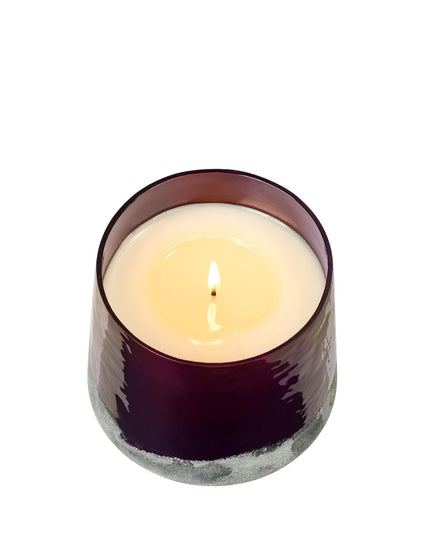 Candle in a purple glass holder on a white background