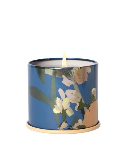Candle in a blue container with floral design on a white background