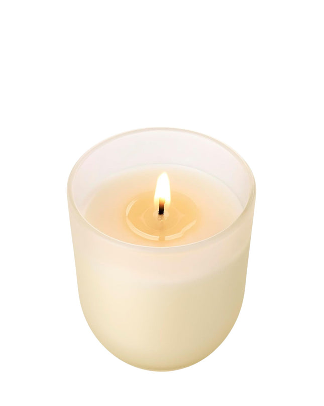 White candle with a lit wick on a white background