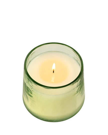 Green candle in a glass holder on a white background