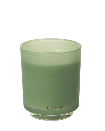 Green candle in a glass container with 'ILLUME' branding on a white background