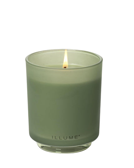 Green candle in a glass container with 'ILLUME' branding on a white background