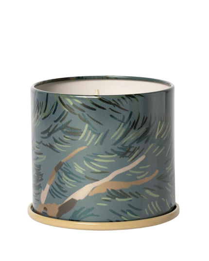 Candle in a decorative tin with leaf pattern on a white background