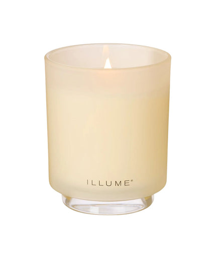 Candle in a beige glass container with 'ILLUME' branding on a white background
