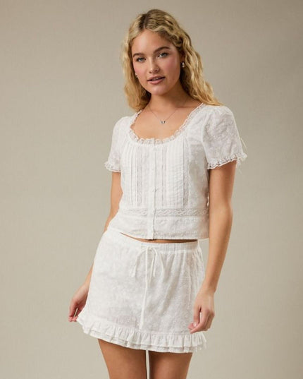 Woman wearing a white lace outfit against a neutral background