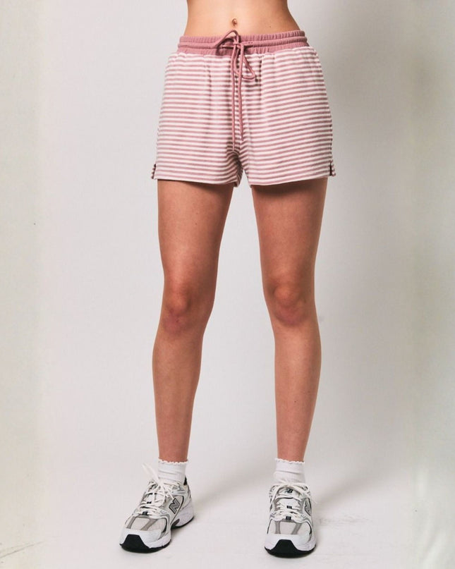 Person wearing pink and white striped shorts on a plain background