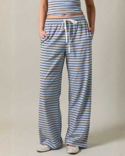 Person wearing blue and white striped pajama pants with a plain background