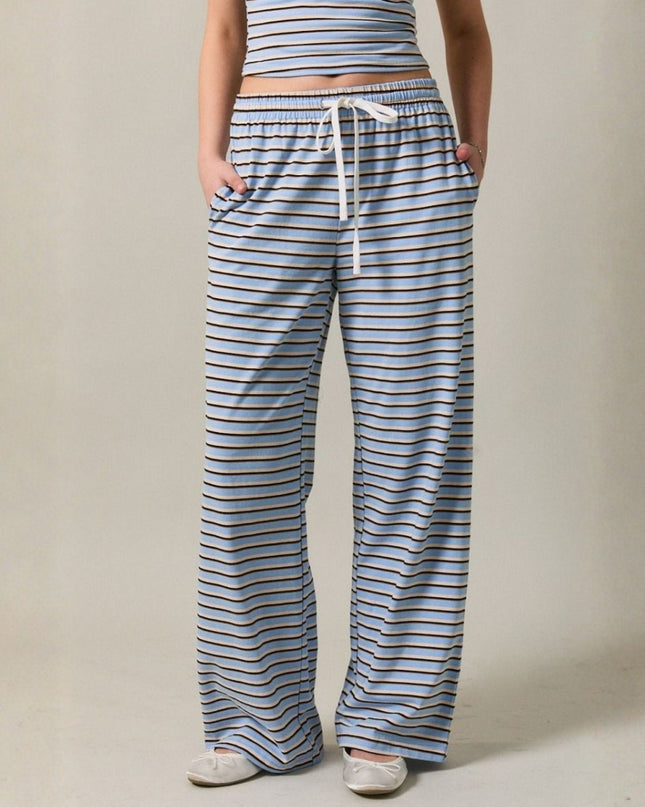Person wearing blue and white striped pajama pants with a plain background