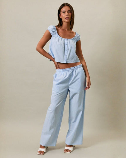 Woman wearing a light blue denim outfit against a beige background