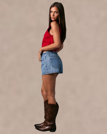 Woman wearing a red top, denim skirt, and brown boots against a beige background
