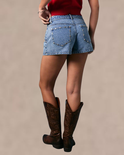 Person wearing denim shorts and brown boots on a beige background