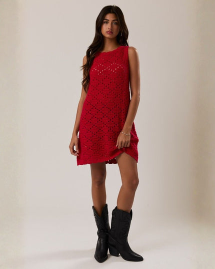 Woman wearing a red dress with black cowboy boots on a plain background