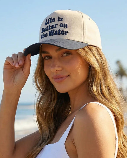 Woman wearing a cap with 'Life is better on the water' text at the beach