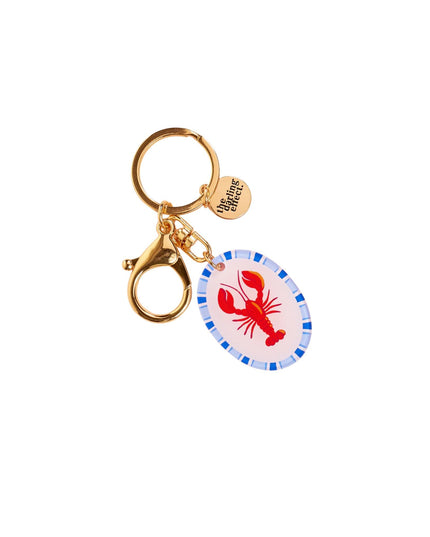 Gold keychain with a red lobster design on a white background