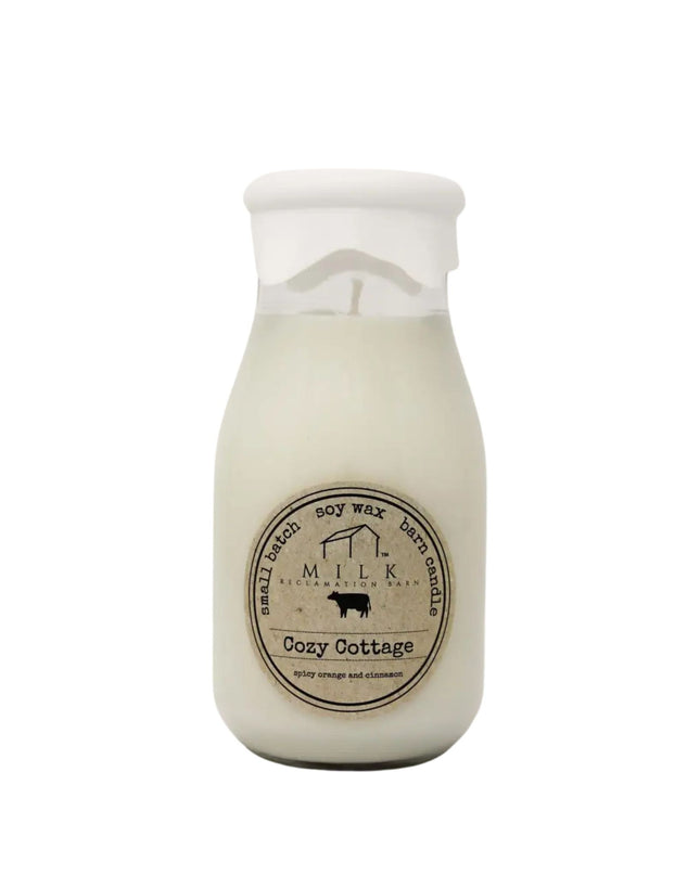 Milk bottle-shaped candle labeled 'Cozy Cottage' on a white background