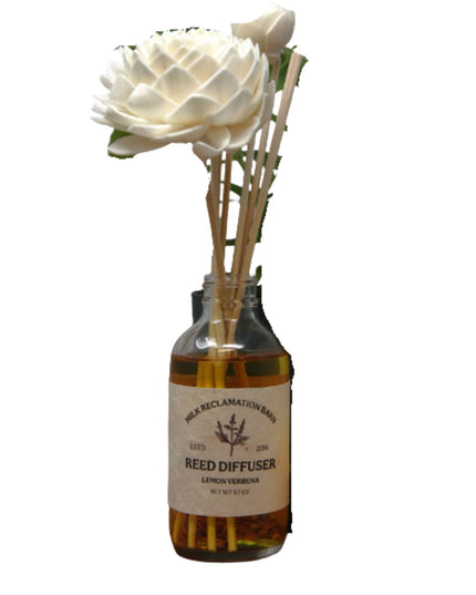 Reed diffuser with a white flower and wooden sticks on a white background