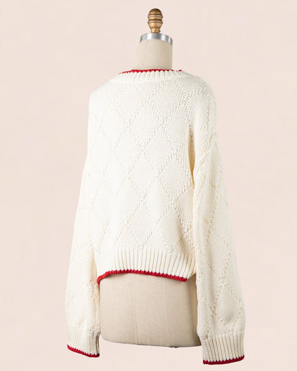 White sweater with red trim on a mannequin against a beige background