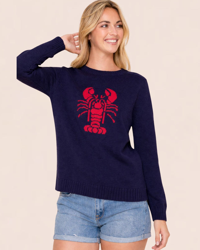 Woman wearing a navy sweater with a red lobster design on a beige background