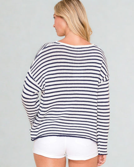 Woman wearing a navy and white striped sweater with white shorts on a gray background