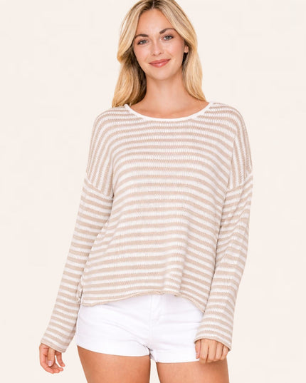 Woman wearing a beige and white striped sweater with white shorts on a plain background