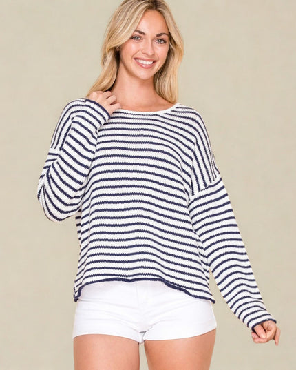 Woman wearing a striped sweater and white shorts on a beige background