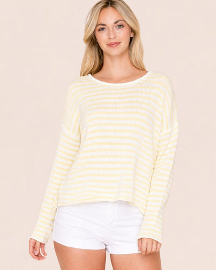 Woman wearing a yellow and white striped long-sleeve top and white shorts on a beige background