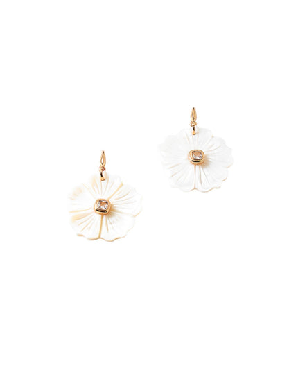A pair of white flower-shaped drop earrings with gold-tone hooks and a small clear stone in the center, shown on a plain white background.