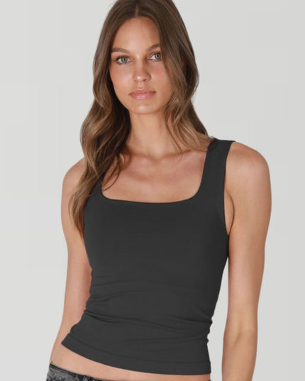 Woman wearing a black tank top against a plain background