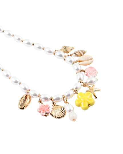 A gold-tone beaded necklace with white faux pearls and colorful seashell and flower charms, including pink, yellow, and white shells, on a plain white background.