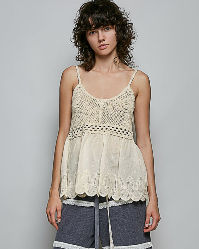 A woman modeling a cream-colored crochet and lace camisole top with thin straps and a scalloped hem, paired with gray shorts, against a solid gray studio background.