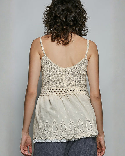 A woman shown from the back wearing a cream-colored crochet camisole top with thin straps and a scalloped lace hem, paired with dark gray pants, against a plain light gray background.