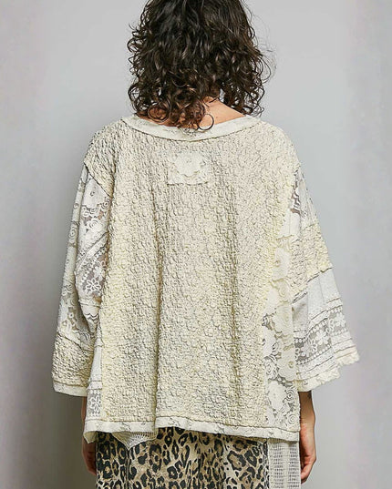 A woman viewed from behind wearing a textured cream-colored patchwork blouse with lace sleeves and a leopard-print skirt, set against a plain gray background.