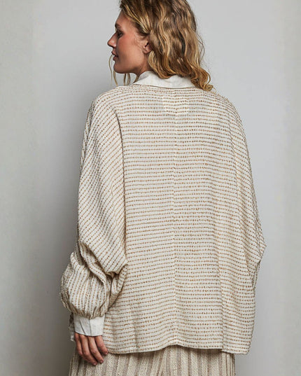 A woman shown from the back wearing a textured, oversized knit cardigan in a warm beige and cream color, paired with a matching striped skirt against a plain light gray background.