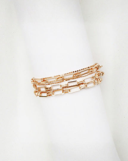 A rose gold multi-band chain bracelet displayed on a white cylindrical mannequin stand against a white background.