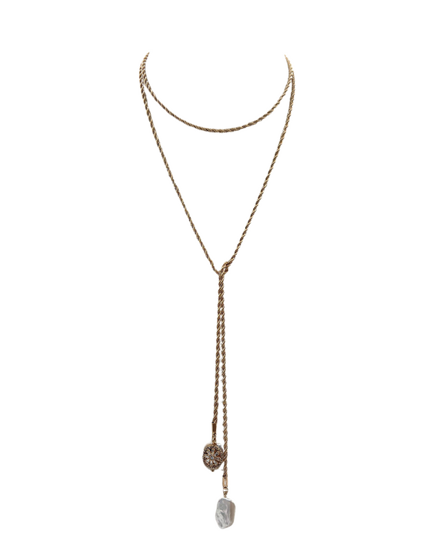A gold-toned double-layered lariat necklace featuring a long dangle chain with a textured circular charm and a polished irregular stone pendant, displayed on a clean white background.