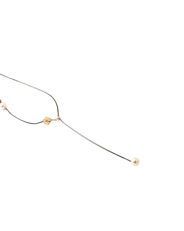 A delicate gold chain necklace featuring a small amber bead, a white pearl bead, and a central gold spacer with a tiny gold bead, ending in a single white pearl drop, shown on a plain white background.