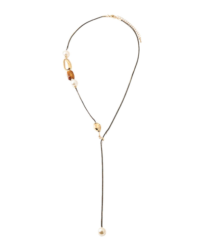 A delicate gold-toned lariat necklace featuring a black cord, a small gold bead, a white pearl, and a polished amber-brown bead, with a long drop ending in a white pearl, shown on a plain white background.