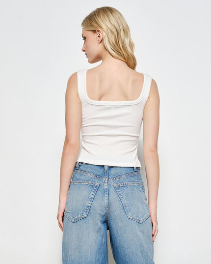 A blonde model shown from the back wearing a fitted white ribbed tank top with a wide scoop neckline and light-wash blue jeans, against a plain light gray studio background.