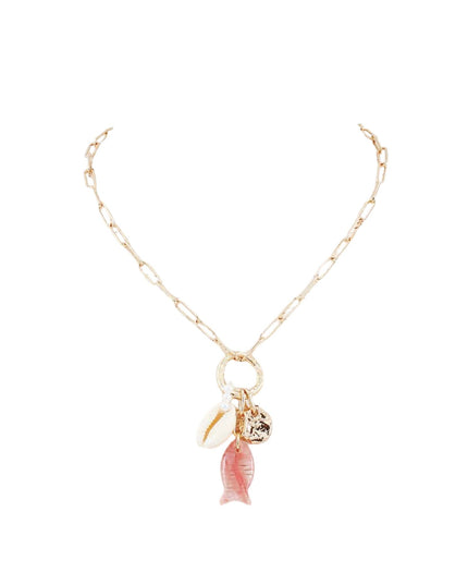 A gold paperclip chain necklace featuring a circular ring pendant with dangling charms, including a white seashell, a small gold bell, and a pink fish charm, set against a plain white background.