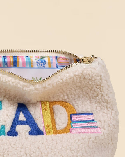 Cream-colored fleece pouch with colorful 'READ' text and zipper on a beige background